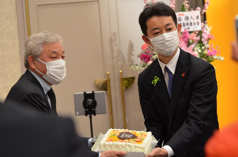 当選祝いのケーキを受け取る熊谷氏(右)=21日夜、千葉市中央区のホテル