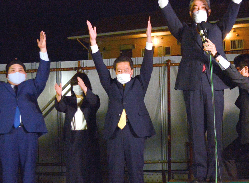 八千代市長に再選され、支援者らと万歳に臨む服部友則氏（中央）＝２３日夜、八千代市内の報告会場