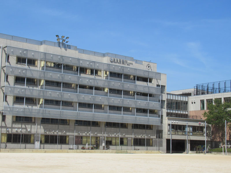 市川市の閑静な住宅街の一角にある校舎。学園名に合わせ、校章のデザインは波間から出る日の出の意匠が描かれている
