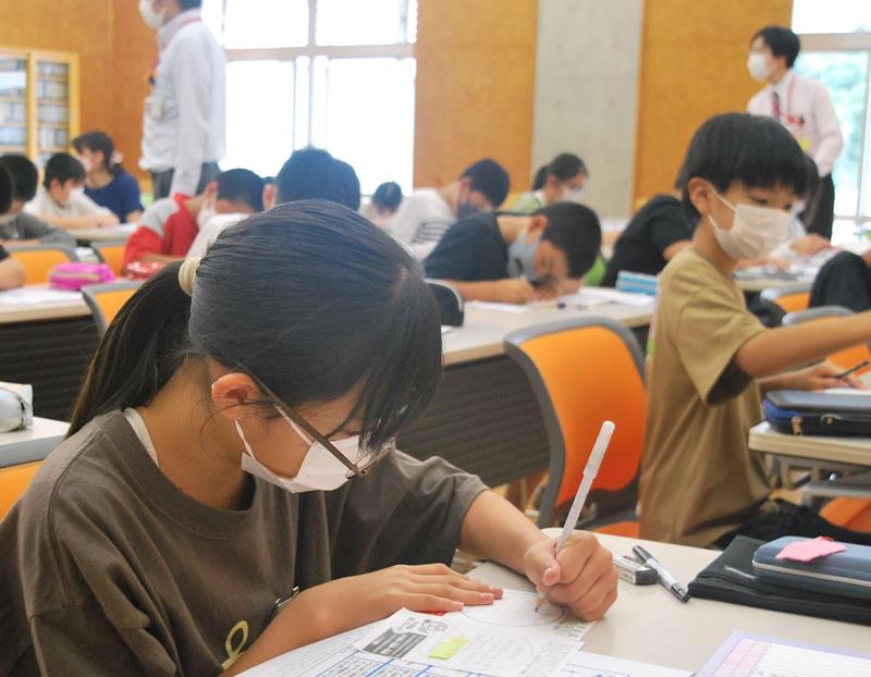電話de詐欺への注意を促すはがきを書く児童たち＝長南町立長南小