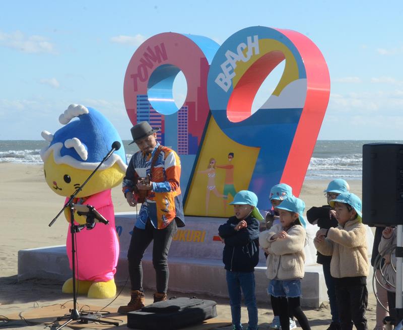 片貝中央海岸に設置された観光オブジェの前で演奏する夫婦ユニット「かのんぷ♪」の中村大介さん＝九十九里町