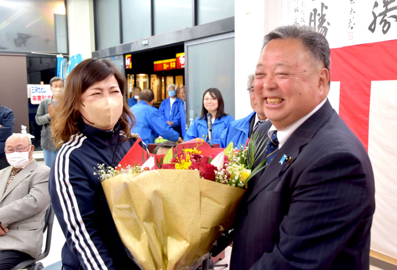 支援者から花束を受け取り、笑顔を見せる三沢氏（右）＝午後９時３５分ごろ、館山市