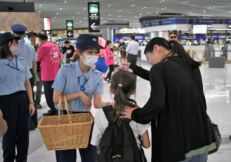 入国時に持ち込み禁止となっている動物などが記されたリーフレットを受け取る旅客（右の２人）＝４日、成田市