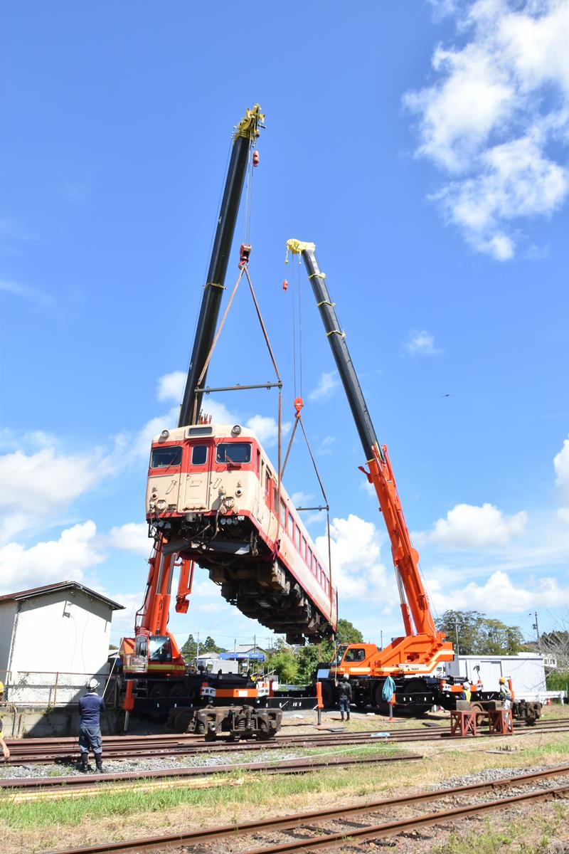 クレーン車2台につり上げられて、前後を180度回転するキハ28=いすみ市のいすみ鉄道国吉駅