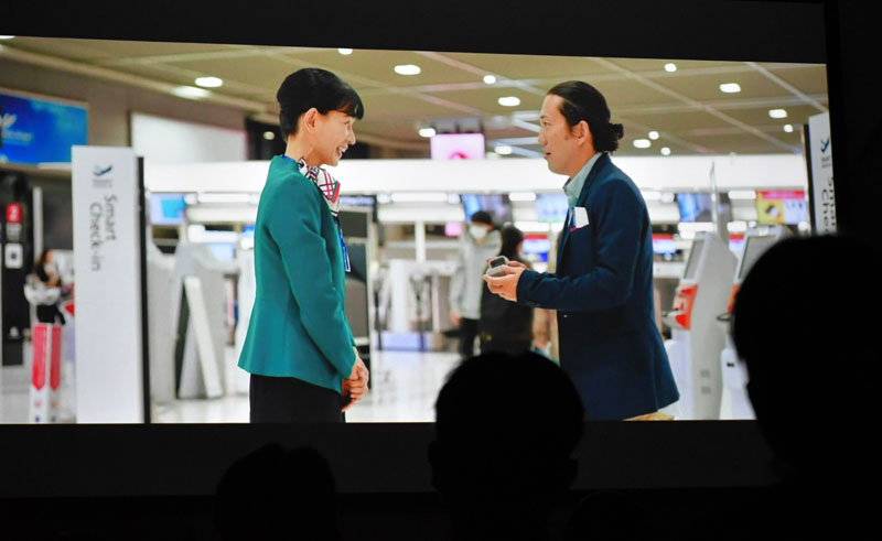 成田空港関連企業による合同就職説明会で初上映された「空の港のありがとう」。旅客がなくした指輪を清水さん演じる地上係員(左)が手渡すシーン=6日、千葉市美浜区の幕張メッセ