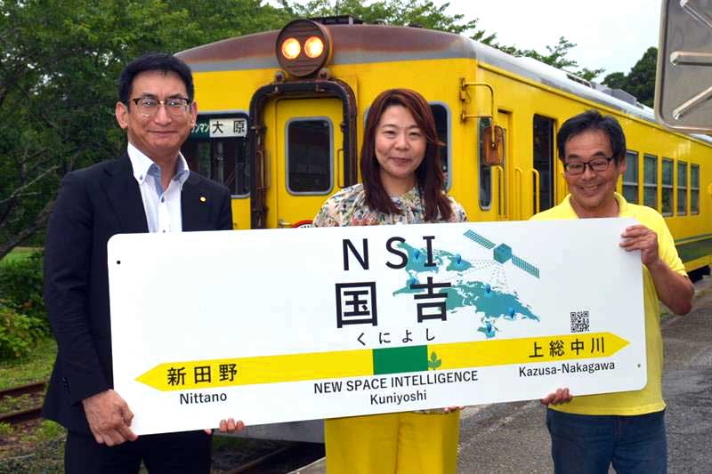 ネーミングライツで「NSI国吉駅」と変更した駅名標を持ついすみ鉄道の古竹社長(左)とNSIの長井社長(中央)=2日、いすみ市