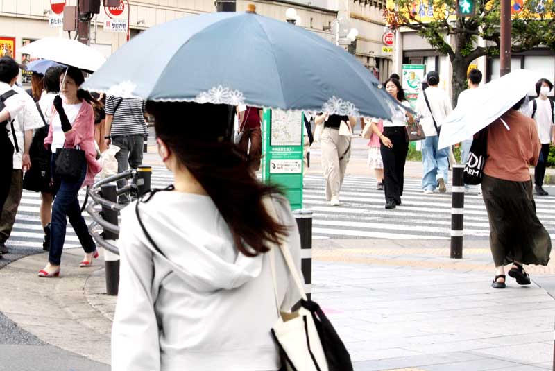強い日差しの中、日傘を差して歩く人たち＝１４日午後、千葉市中央区