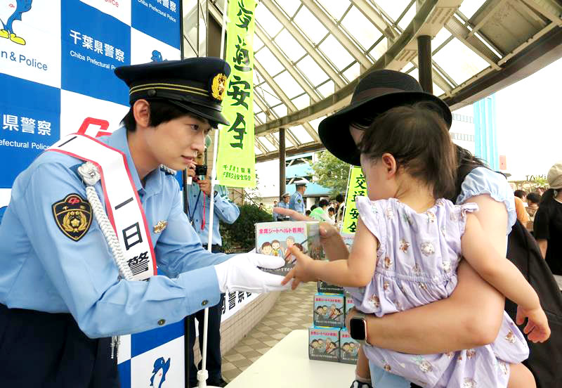 一日署長の福尾誠さんからティッシュを受け取る親子=21日、千葉市緑区