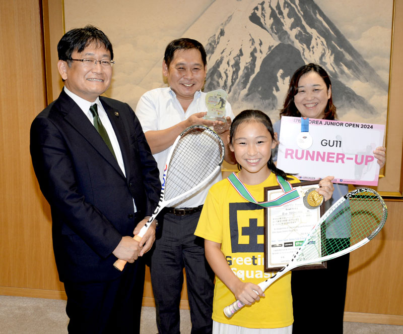 スカッシュの国際大会で初優勝し、神谷市長(左)にメダルを携えて報告した吉野莉央さん(手前)。後ろは競技生活を支える両親=千葉市役所