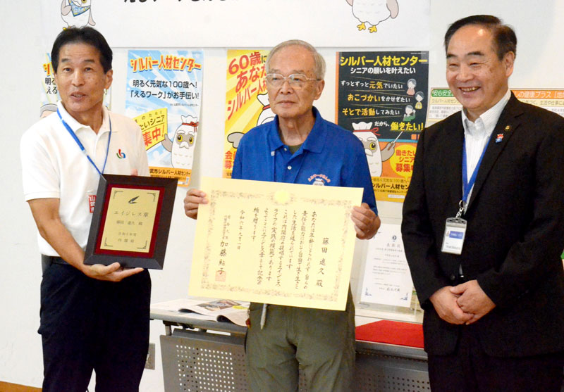 内閣府から贈られた「エイジレス章」の賞状を手にする藤田さん(中央)。右は松下市長=山武市