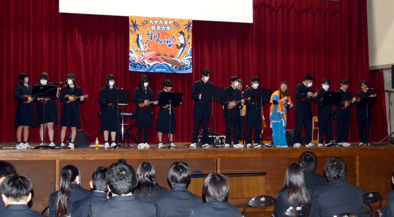 九十九里町観光大使の音楽ユニット「かのんぷ♪」と一緒に壇上でウクレレを演奏する生徒ら=同町