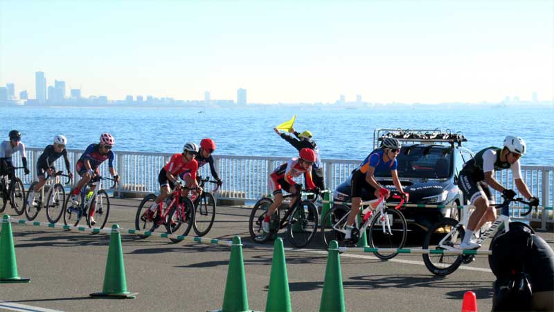 東京湾を背景にコースを疾走する選手たち=30日、浦安市