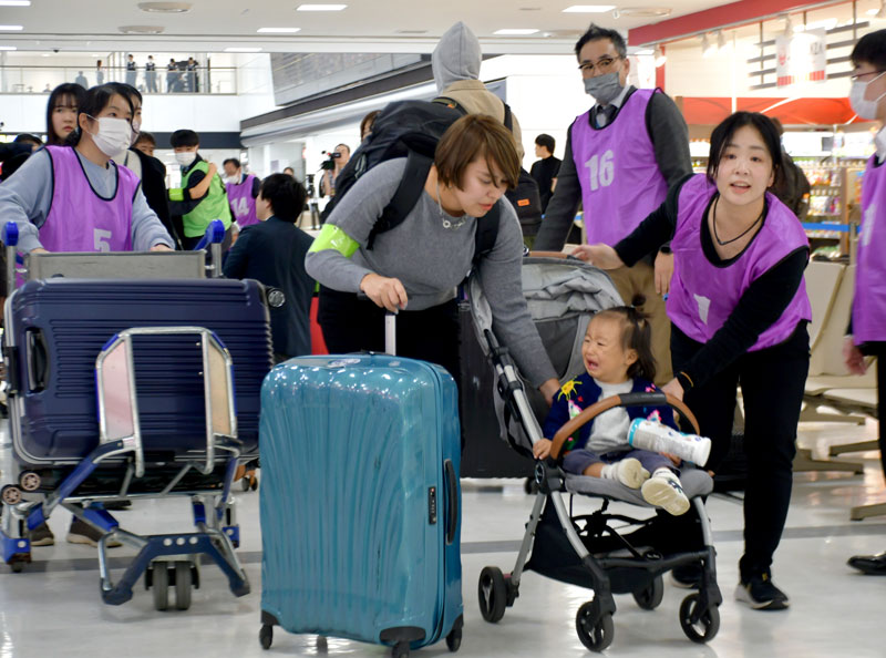 巨大地震が発生したという設定の中、成田空港でおびえる親子を誘導する訓練参加者ら＝６日、成田市