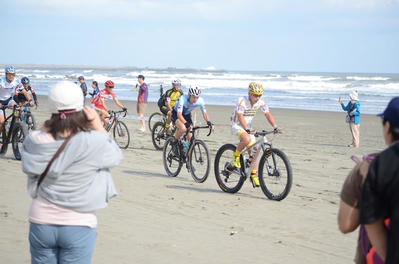 砂浜を自転車で周回するスポーツ「ビーチクロス」で、九十九里浜を走る選手ら＝１０月１４日、九十九里町