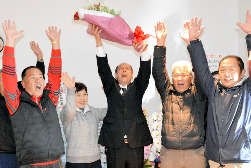 御宿町長選で初当選し花束を手に万歳三唱する原氏（中央）＝１５日夜、御宿町の事務所
