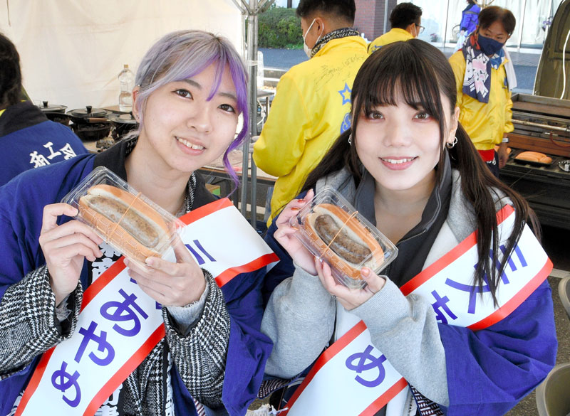 佐原商工会議所青年部が手掛けたホットドッグをブースで手渡したミスあやめ＝香取市