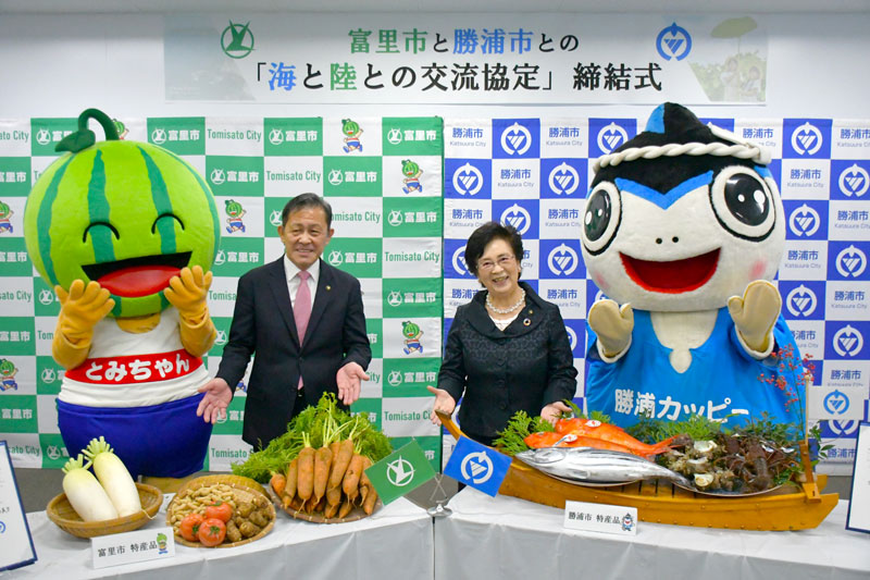 交流協定の締結式で特産品を紹介する富里市の五十嵐市長（左）と勝浦市の照川市長＝富里市役所