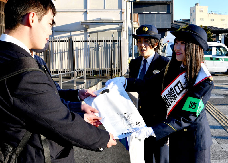 年末年始を前にＪＲ佐原駅前で防犯などへの注意を呼びかける石井さん＝香取市