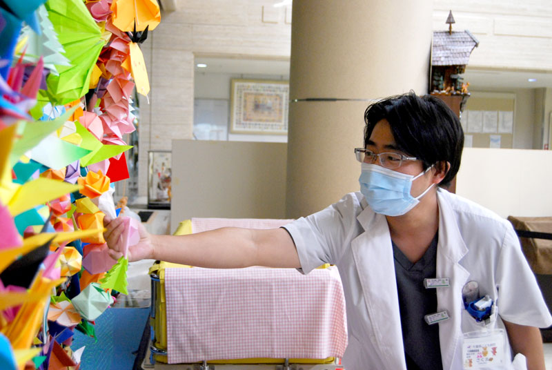ツリーを織りなす折り紙作品を手に取る県こども病院医師の佐久間昭利さん
