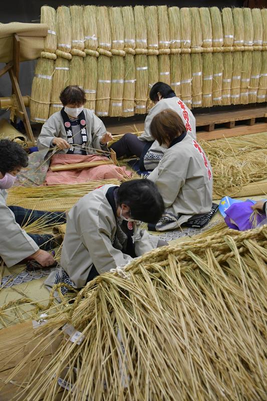 細いしめ縄を丁寧に編んでいく成田山新勝寺の奉仕員ら=1日、成田市