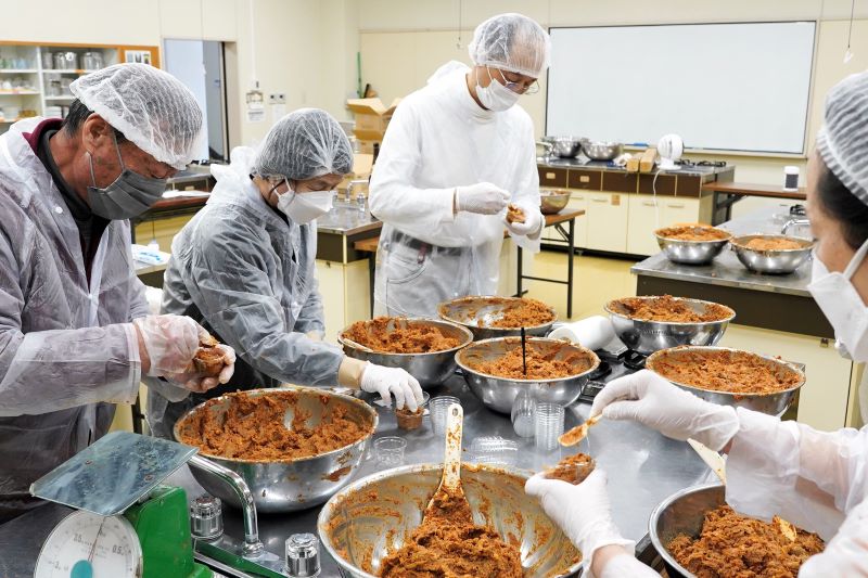とがらしごぼうの調理でキャップやマスクを着用して手を動かす住民＝１１日、旭市