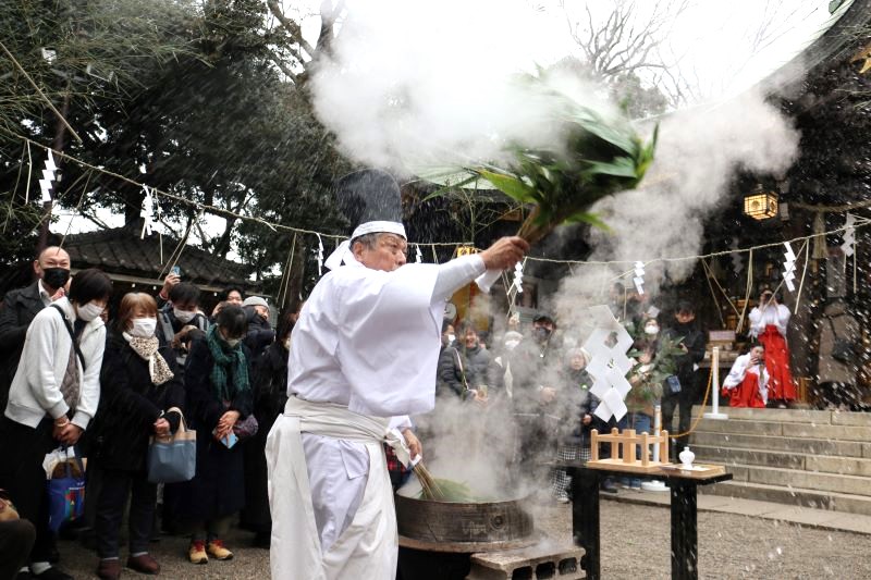 100年ぶりに復活した検見川神社の湯立て神事。巫子の友野さんが湯に浸したササを振りまき、厄落としの効果があるとされる湯を人々にかけた=19日、千葉市花見川区