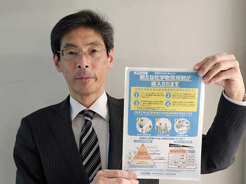 化学物質の新規制が導入されたことを伝えるパンフレットを手にする県労働局の関副主任＝４日、千葉市中央区の千葉労働局