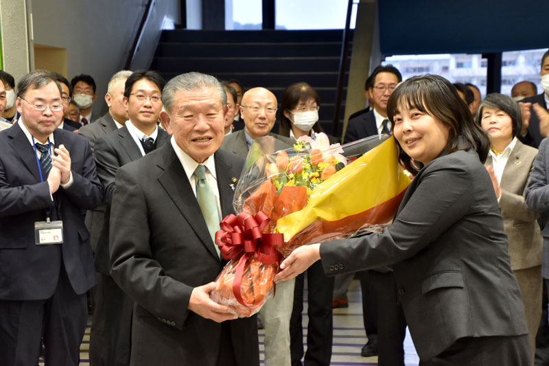 市職員から花束を贈られ笑顔を見せる長谷川氏（左）＝１１日、鴨川市役所