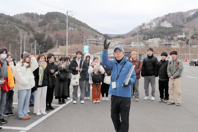 敬愛大学の学生に震災当時の様子を伝える田村孝行さん（中央手前）＝２月１２日、宮城県女川町（敬愛大学提供）