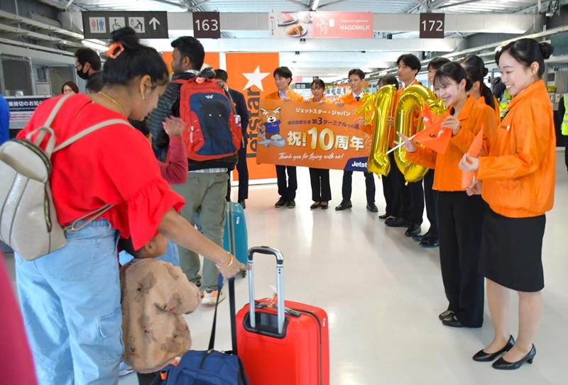 成田空港第3ターミナル開業10年を記念し、搭乗ゲートで旅客を見送るジェットスター・ジャパンの新入社員ら=7日、成田市