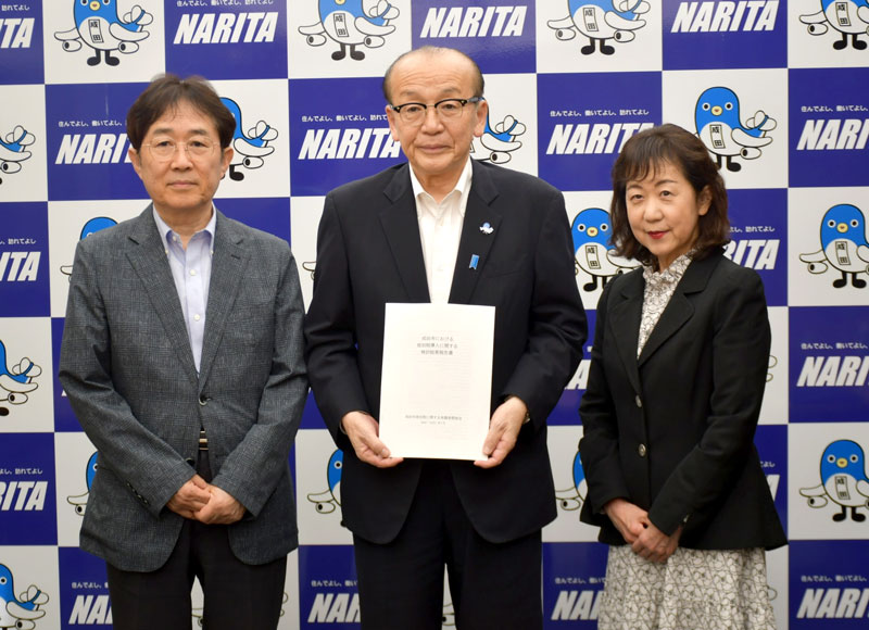 成田市の小泉市長(中央)に市独自の宿泊税導入に関する検討結果報告書を提出した有識者懇談会の星野会長(左)と千葉経済大短期大学部教授の影山美佐子副会長=28日、同市役所