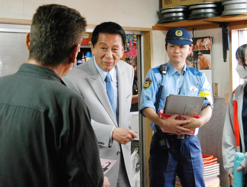 海外からの着信電話に注意を呼びかけるチラシを住民に手渡し、説明する杉さん=21日、千葉市中央区都町