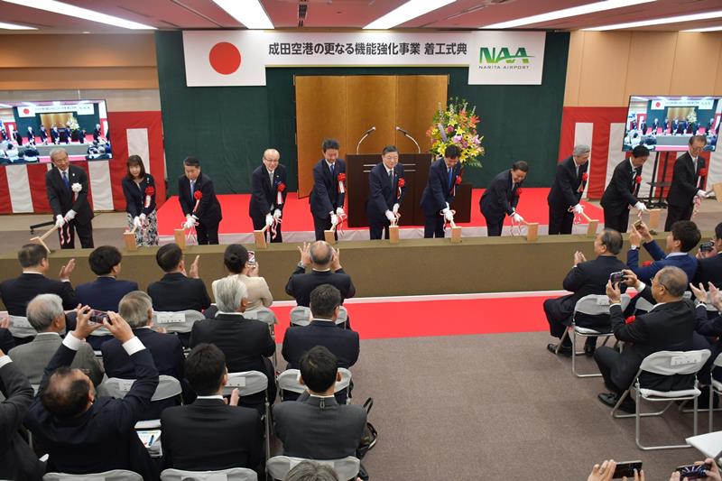 成田空港のC滑走路新設とB滑走路延伸を行う機能強化の本格工事開始を記念した着工式典でくわ入れする関係者=25日、成田市のNAA本社