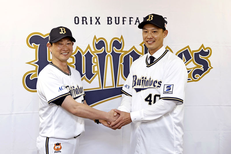 トレードで中日からオリックスに入団し、記者会見で岸田監督（左）と握手する岩崎翔投手＝ほっともっと神戸（共同）